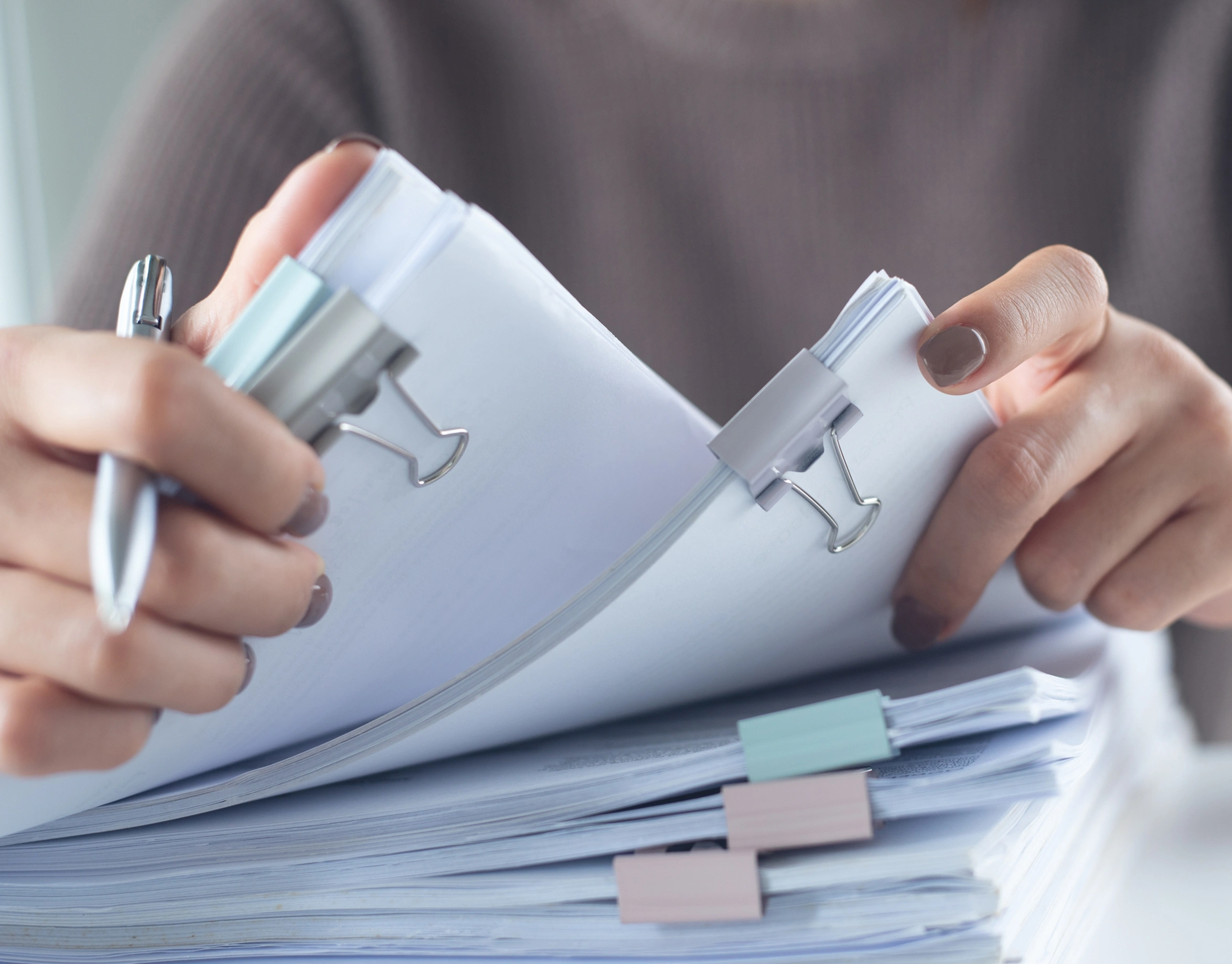 A person holds a clipboard with a stack of papers, indicating they are reviewing or organizing documents.